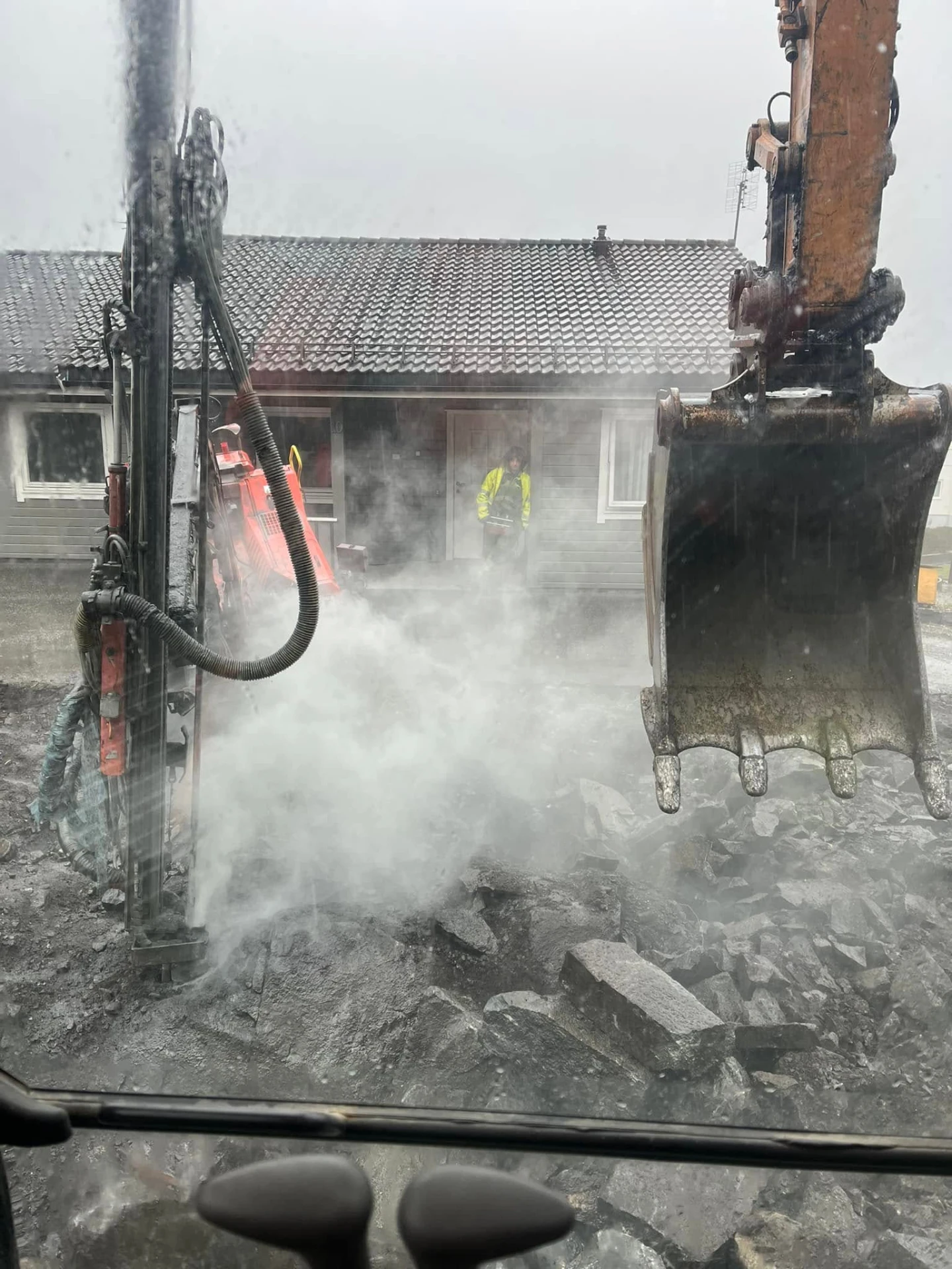 Boring og sprenging av fjell foran bustad med gravemaskin