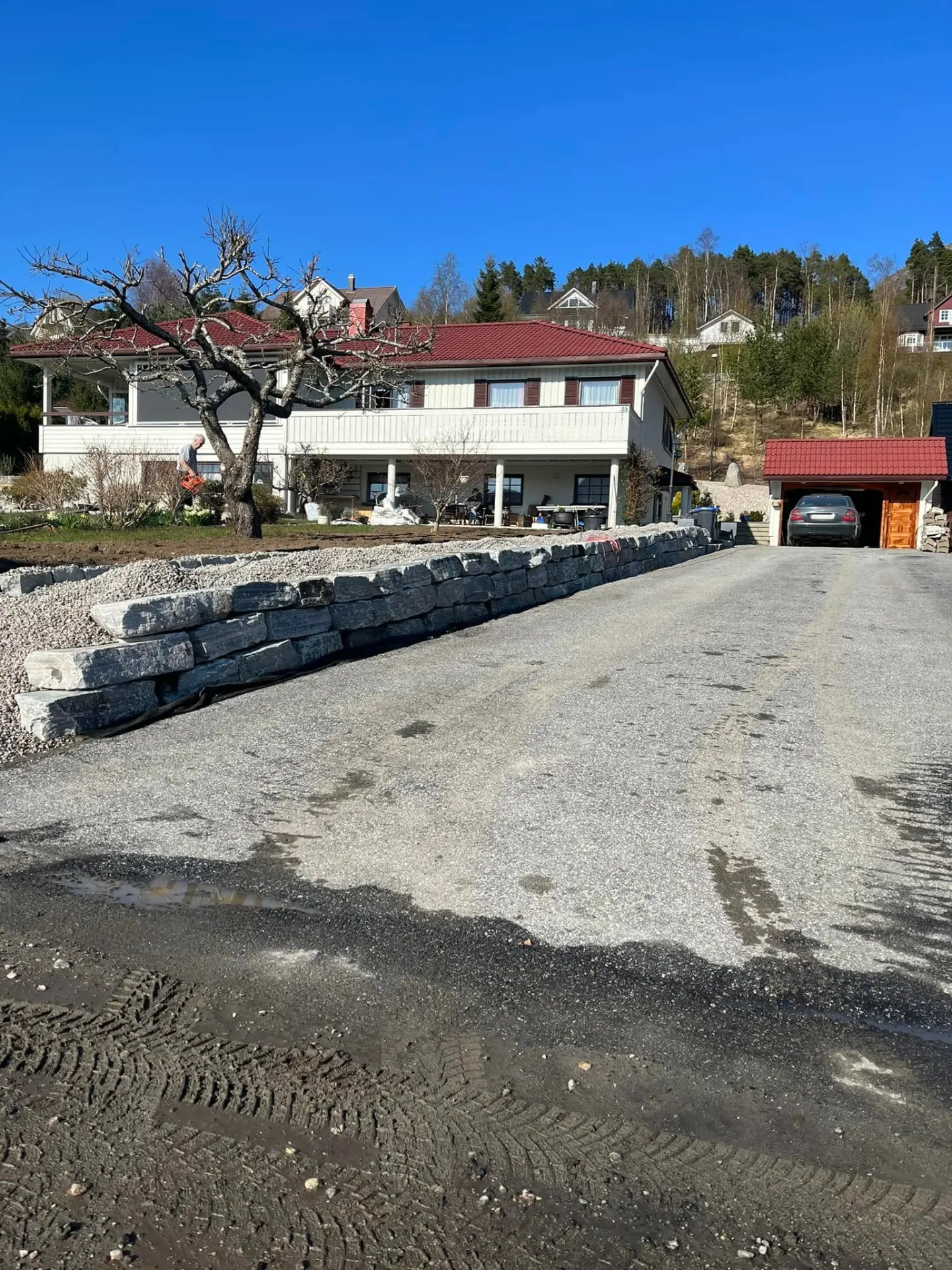 Natursteinsmur langs gruslagt innkøyrsel ved bustad