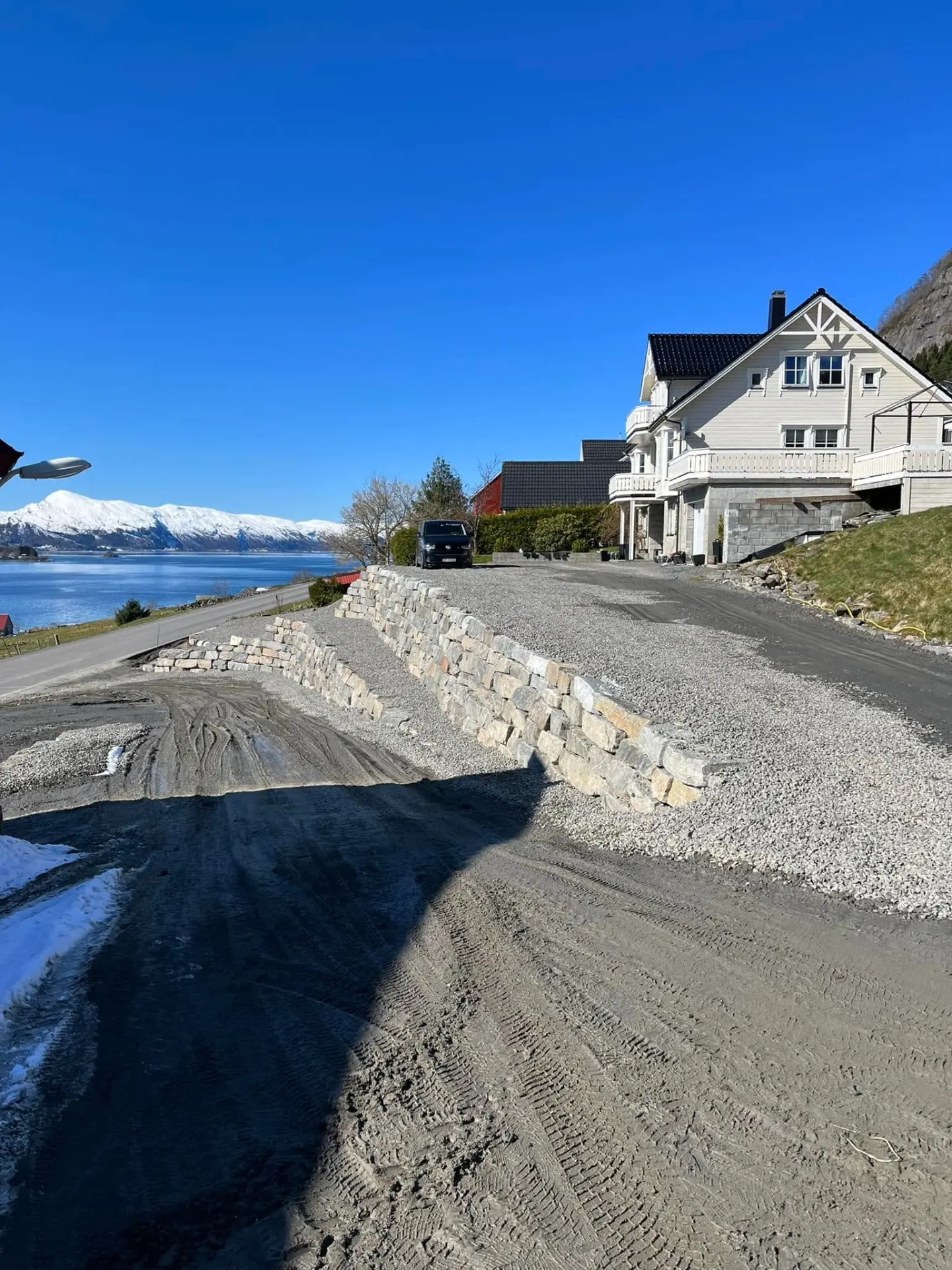 Natursteinsmur og planert uteareal ved hus og fjord i Volda