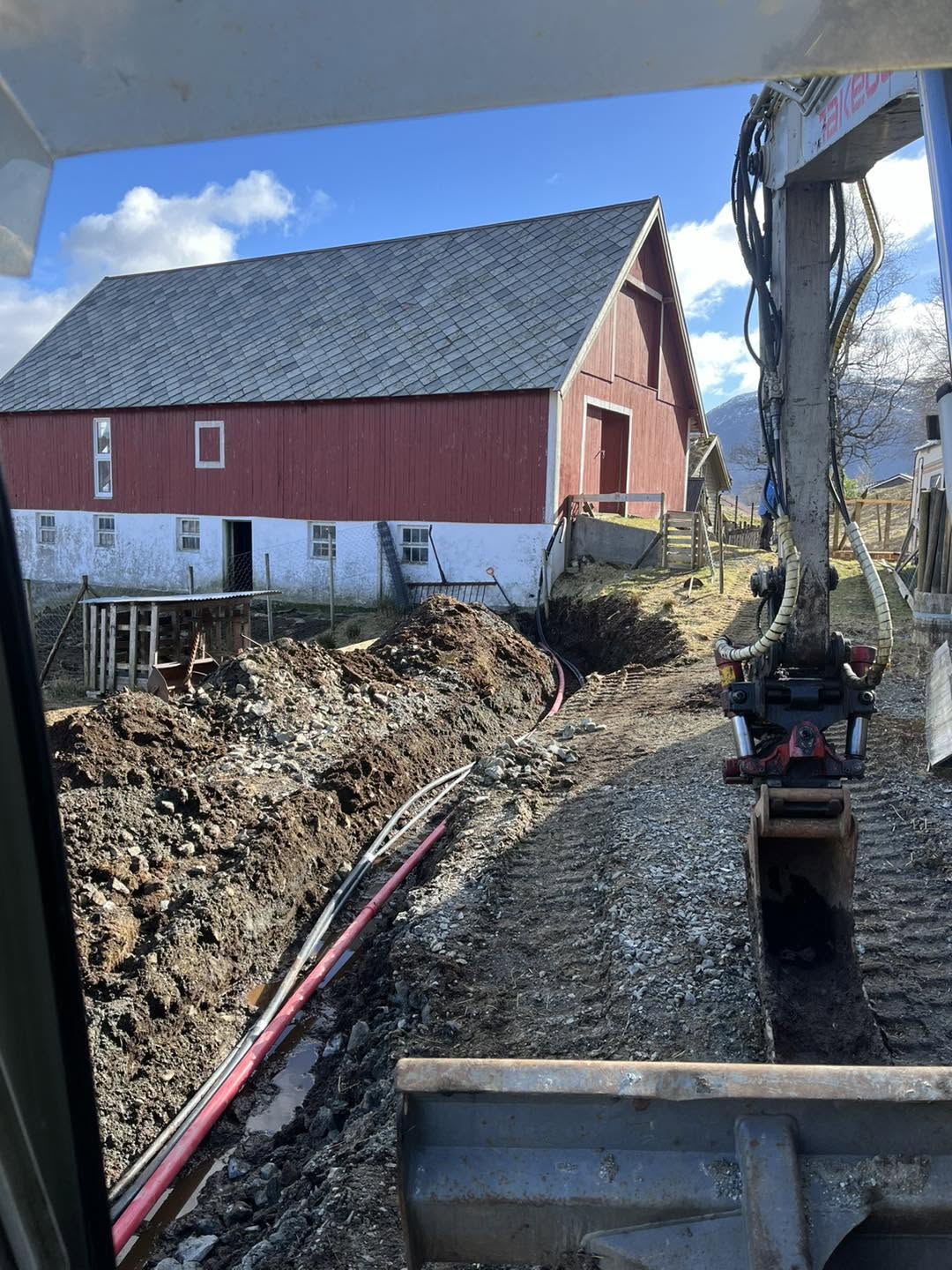 Grøftegraving langs den raude garden med røyr og kabel lagt i grøfta og gravemaskina på plass